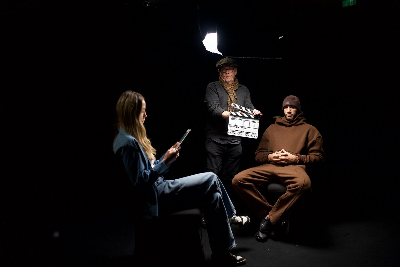 An interview being filmed on a dark studio set with a clapperboard