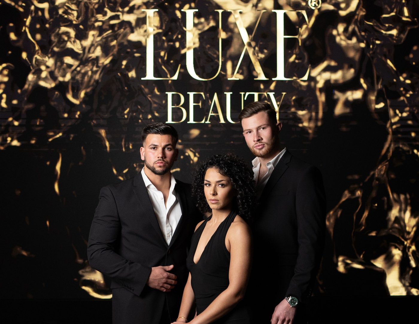 Three people photographed in front of a gold backdrop for Luxe Beauty